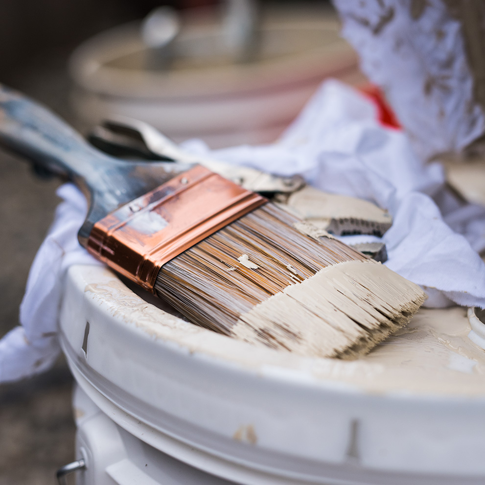 Image of a paint brush on top of a 5 gallon can