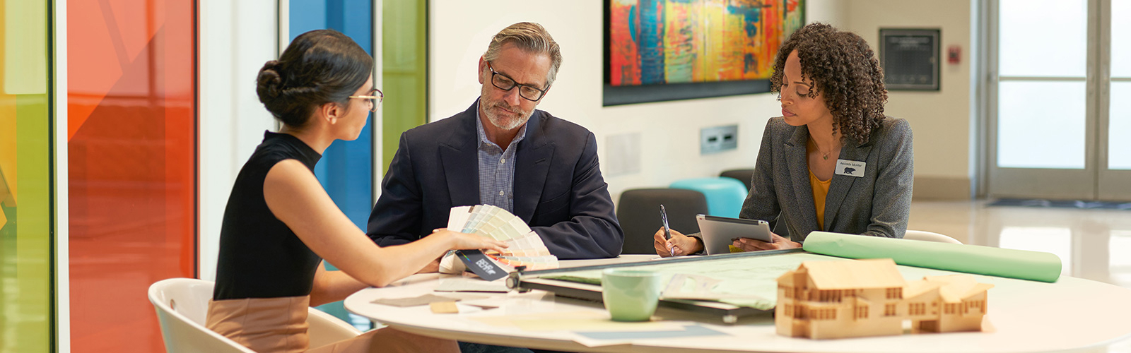 Large image of 3 seated architects in an meeting room discussuing colors and looking at a BEHR Fan Deck