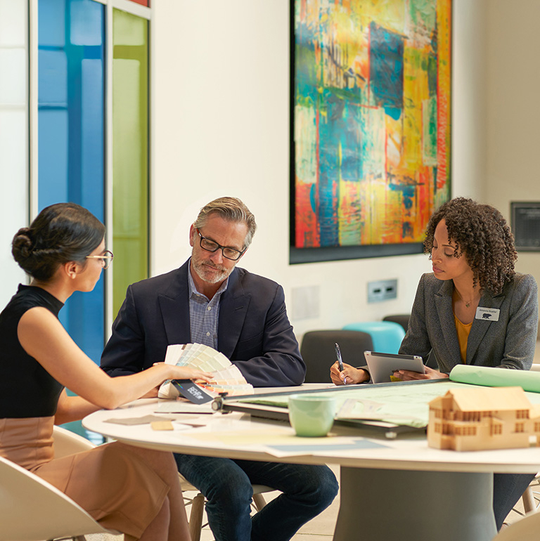 Small image of 3 seated architects in an meeting room discussuing colors and looking at a BEHR Fan Deck