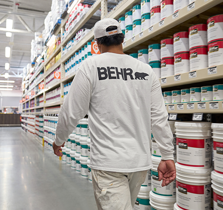 Mobile view of a pro painter spray painting the exterior wall of a house.