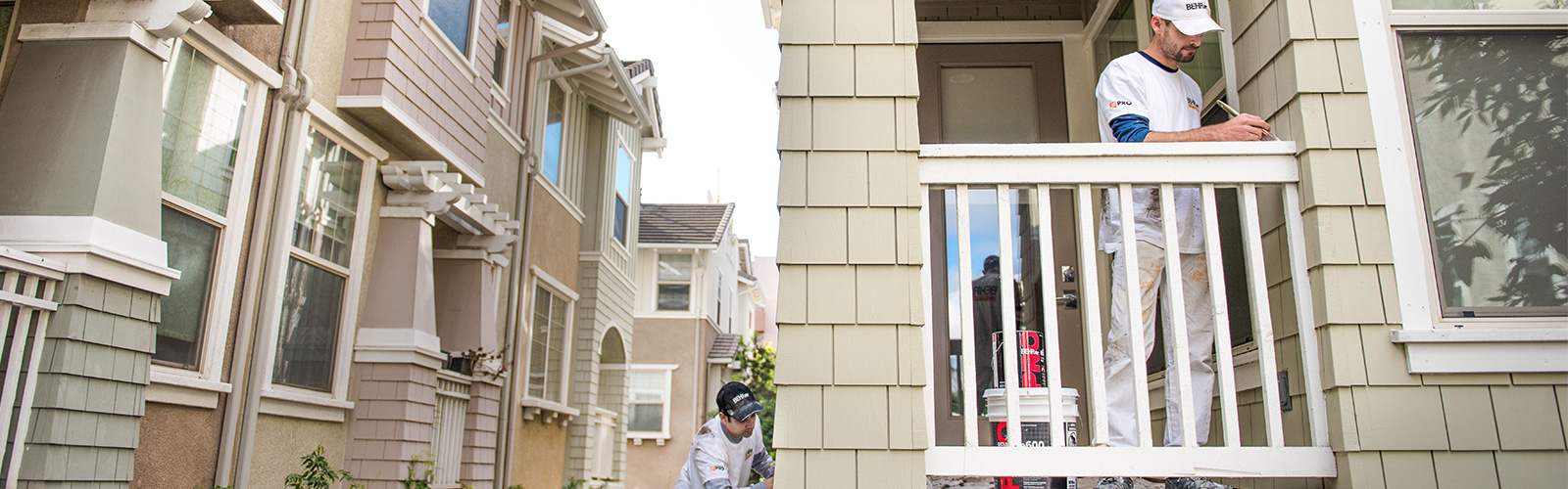 Large image of 2 Pro painters painting the wooden railings of the exterior of an apartment block.