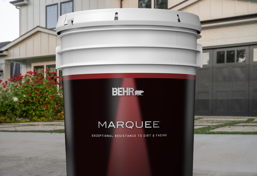 Image of a 5 gallon can shot of BEHR MARQUEE in front of a house.
