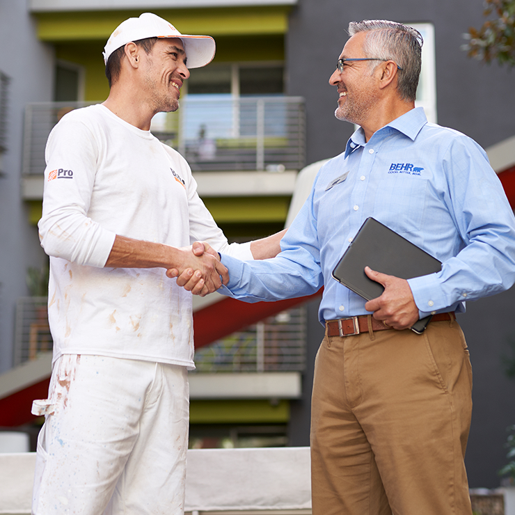 A BEHR PRO Rep shaking hands with a Pro Painter.