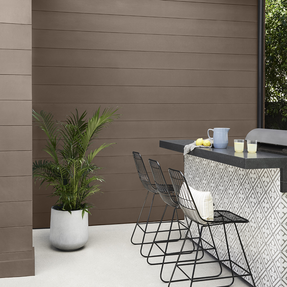 A brown house exterior and black bar painted with Behr Dynasty Exterior paint