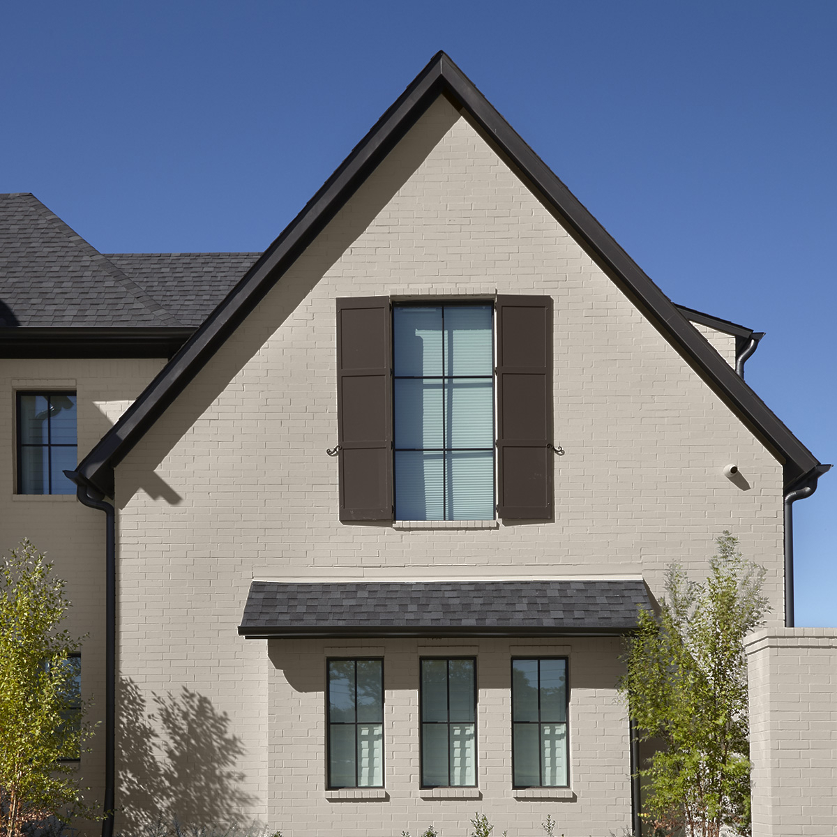A neutral house exterior and brown shutters painted with Behr Dynasty Exterior paint