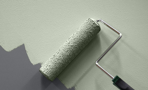 Painting over a dark gray wall with a muted green color