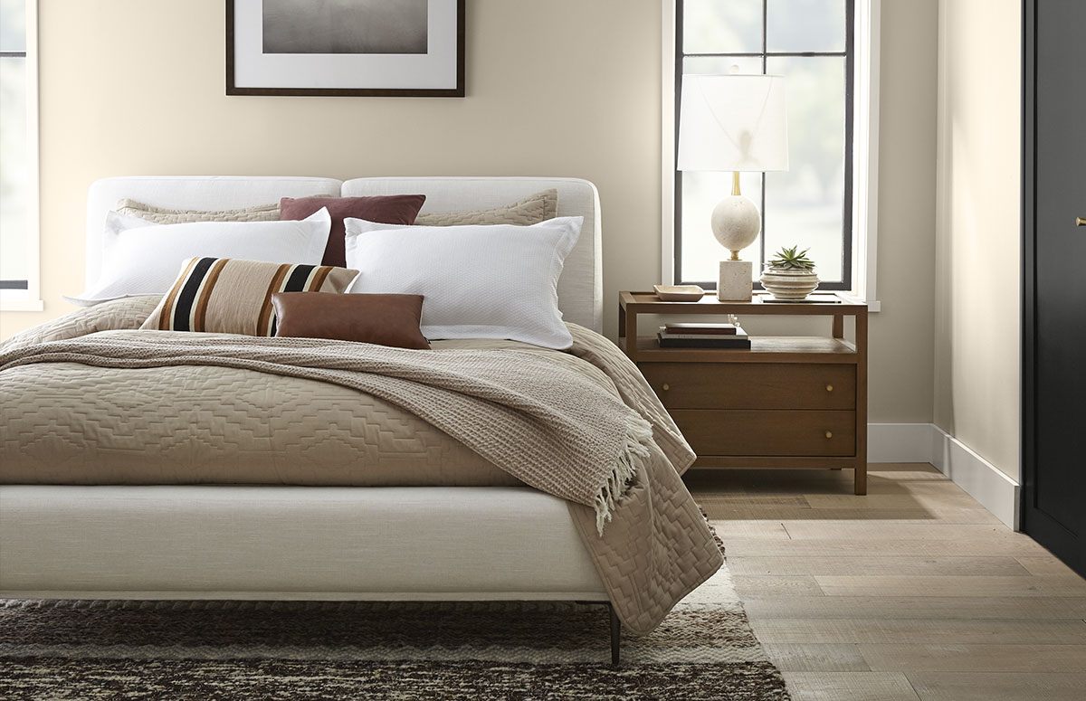 Serene bedroom showcasing a modern organic aesthetic with Swiss Coffee trim, Even Better Beige walls, warm wood accents, and neutral layered bedding.
